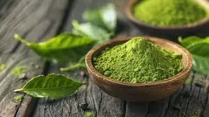 Green tea leaves and matcha-style green powder in a wooden bowl